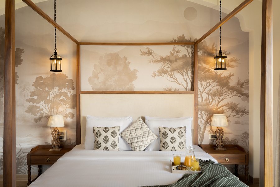 Wooden four-poster bed against a hand-painted tree mural
