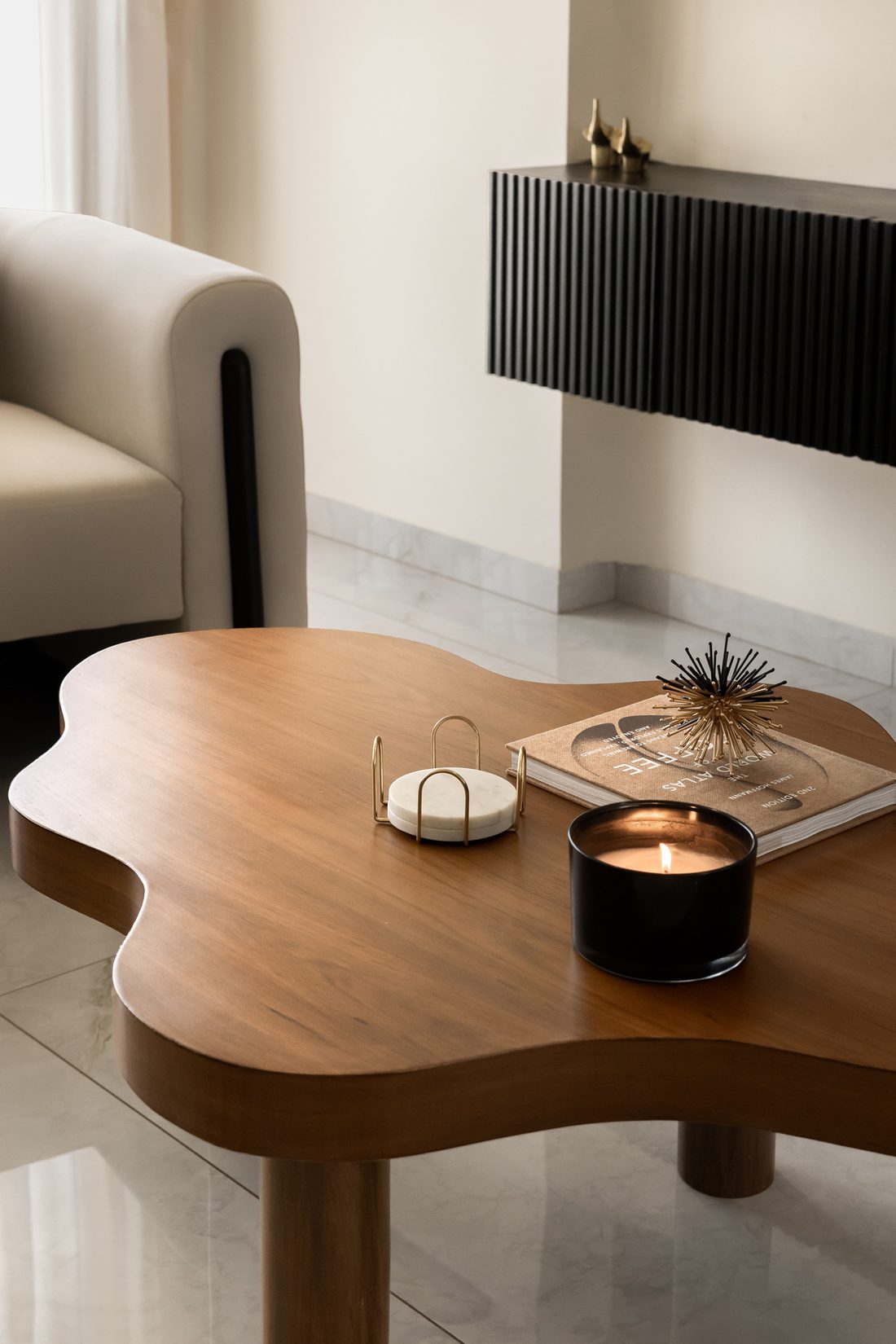 Black fluted wall cabinet above an organic-form wooden coffee table