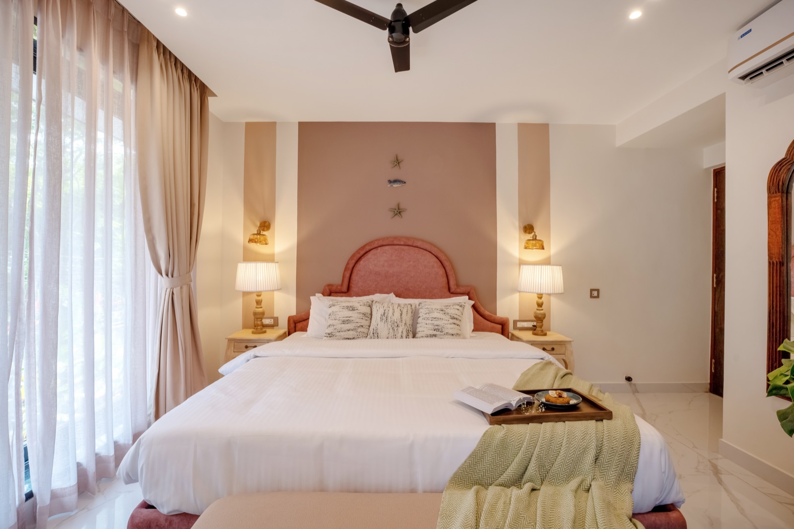 Bedroom with arched rose headboard and soft daylight through sheer curtains