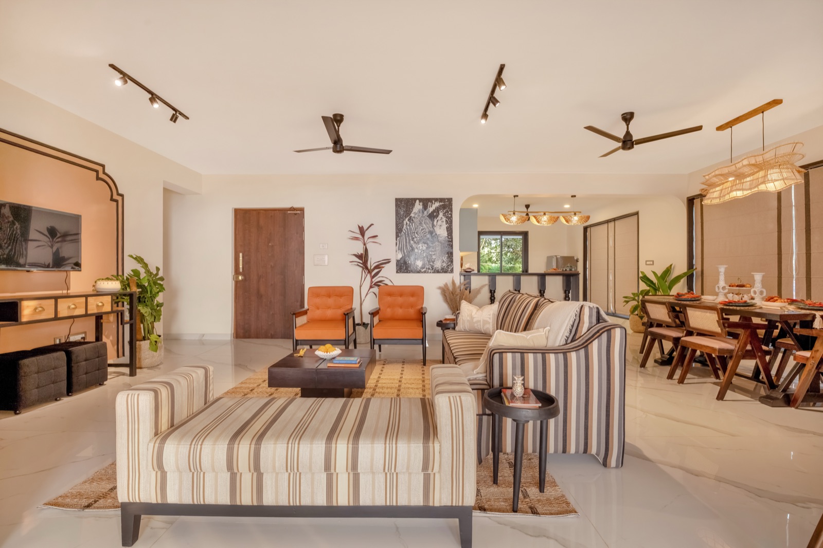 Open living room with striped daybed, cane bar stools and warm white walls