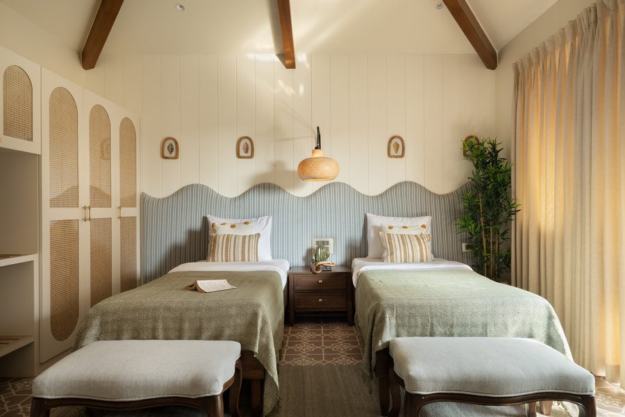 Twin bedroom with scalloped sage headboard and cane wardrobes