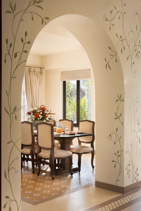 Arched passage hand-painted with trailing vines, dining room beyond